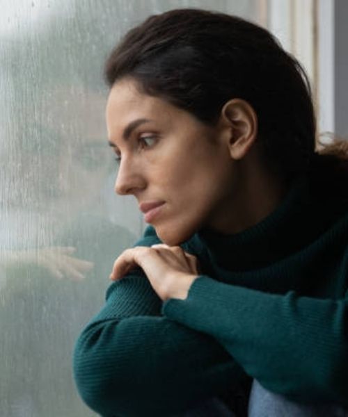 Frau schaut nachdenklich aus dem Fenster (2)